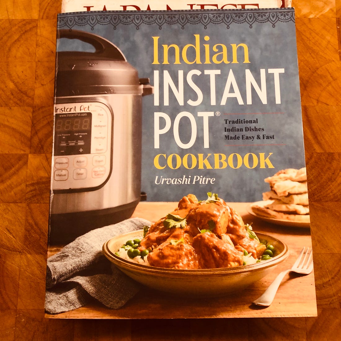 The cover of Indian Instant Pot Cookbook, showing an Instant Pot, some naan, and a bowl of curry