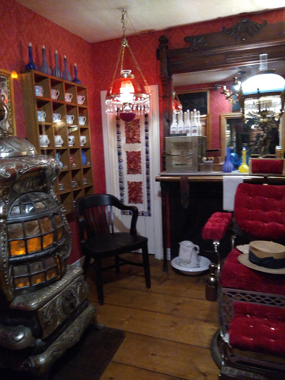 Victorian barbershop with chair, small bottles on shelves, and potbellied woodstove