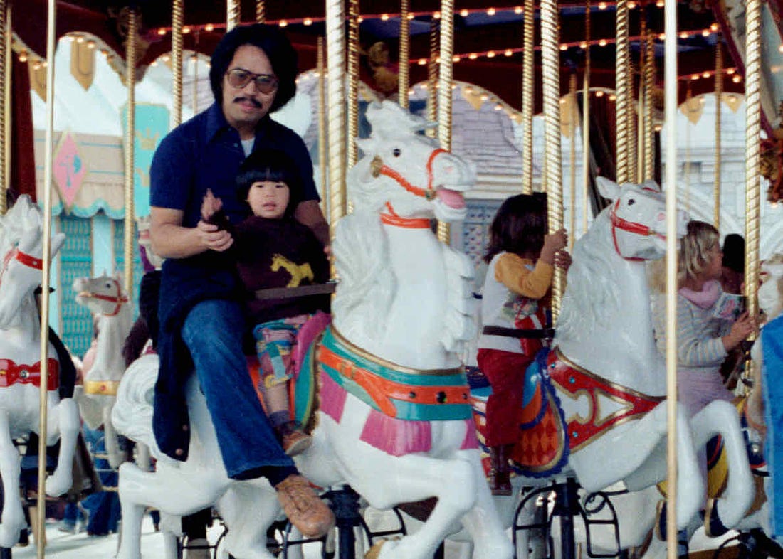 Little Jeff riding a white horse on King Arthur's Carousel with his dad