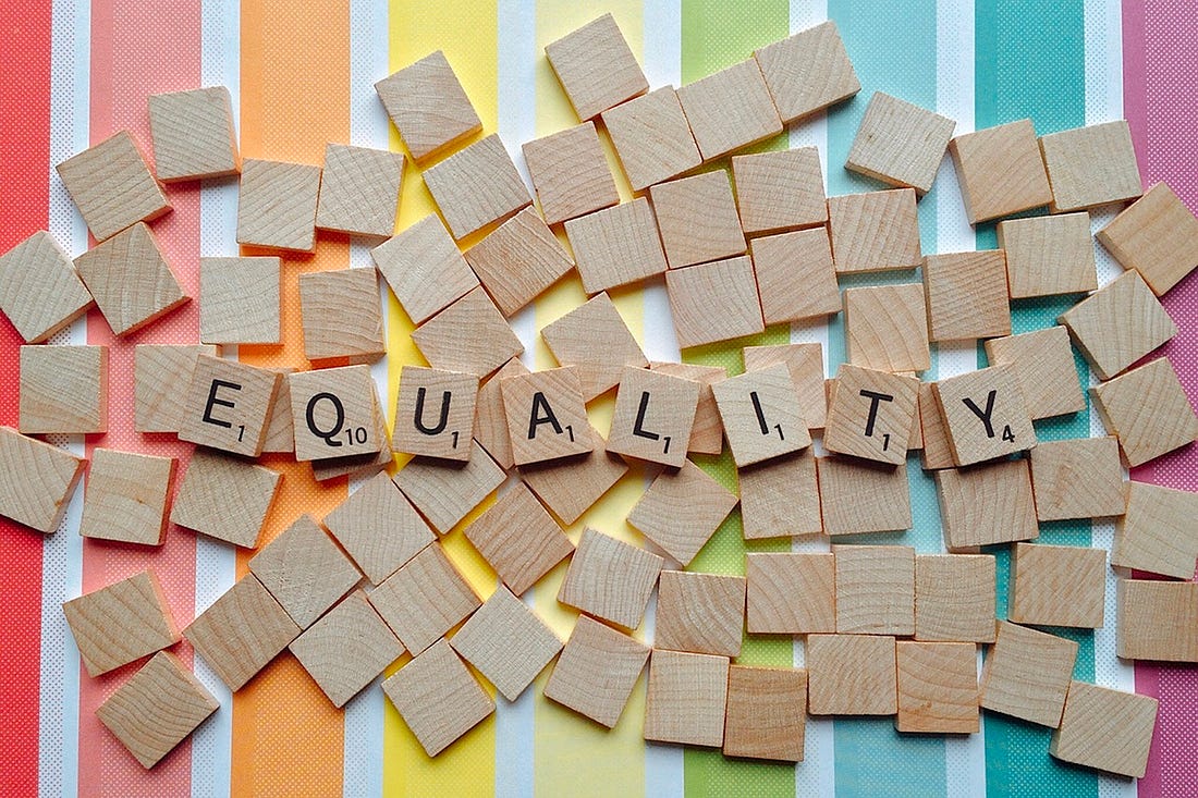 Equality spelled on scrabble letters with rainbow background