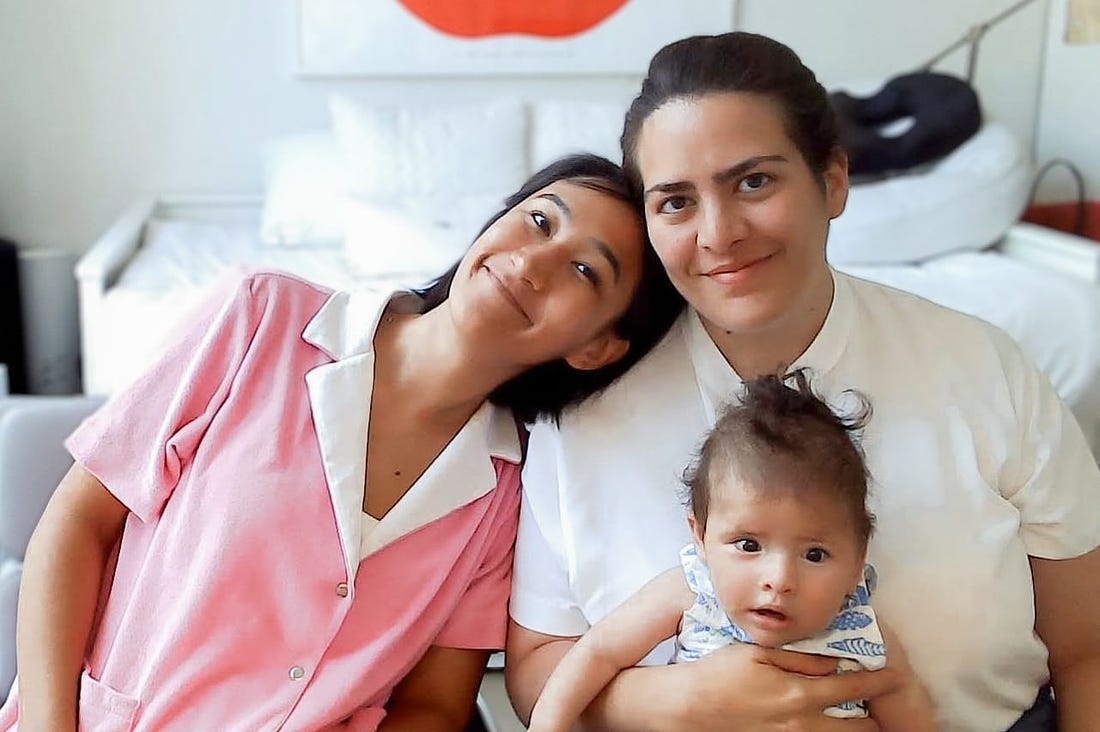 A photograph of two mothers with their young baby.