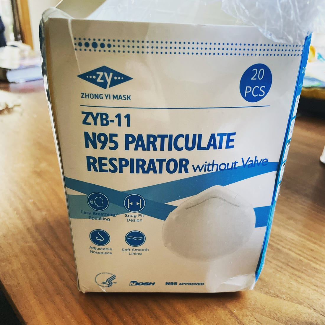 An open and slightly distressed box of N95 masks. The blue lettering on a white box reads, in part, “Zhong Yi Mask, ZYB-11, N95 Particulate Respirator without valve”