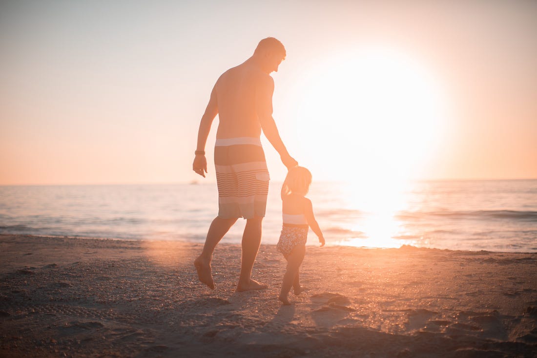image of a dad with his child on the beech at sunset for article by Larry G. Maguire