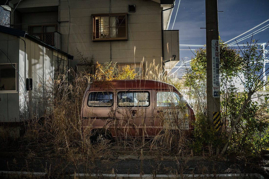 Photo of an overgrown abandoned minivan in Fukushima Japan.