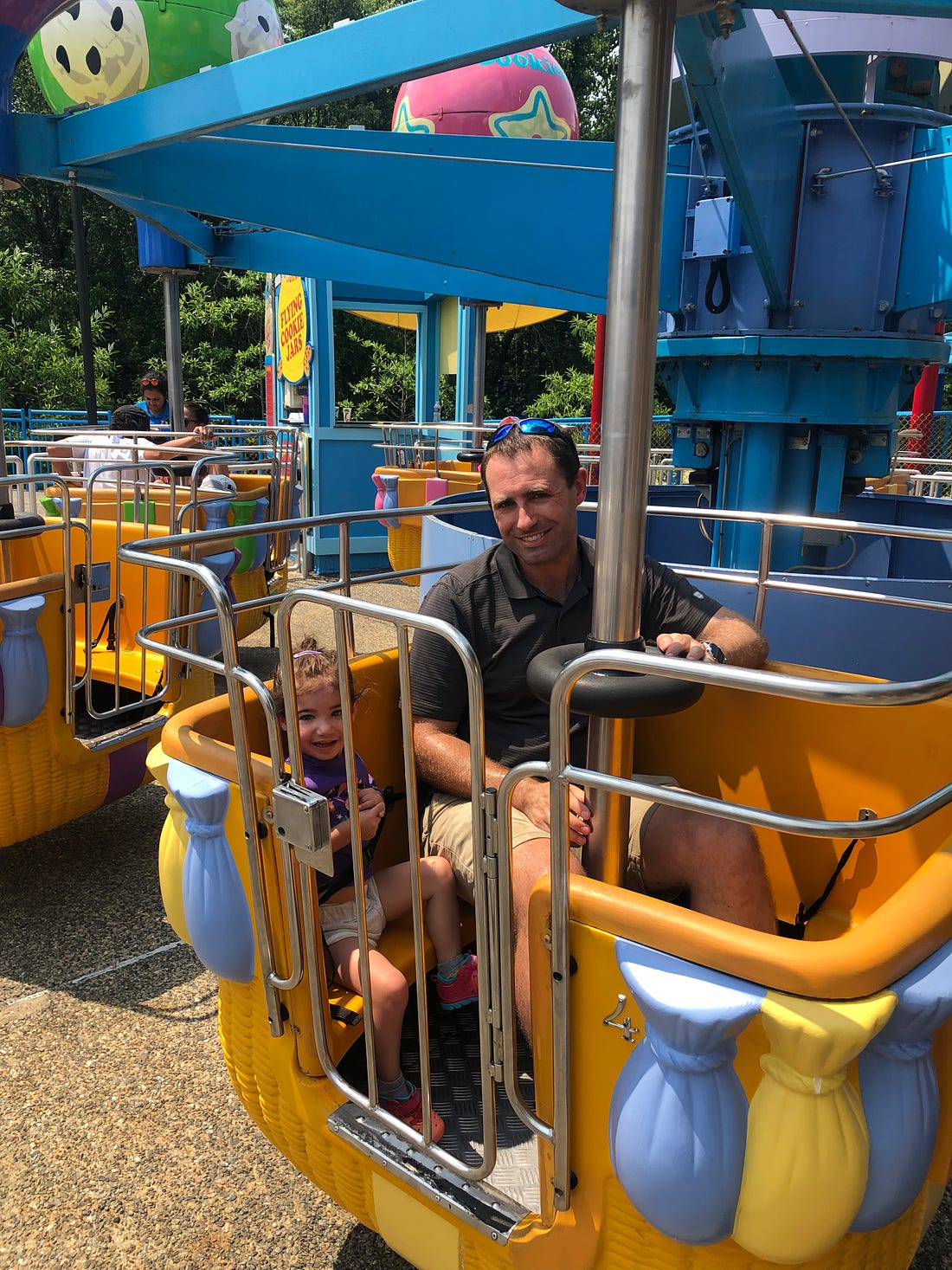 Photograph of Lila and Mark on a ride.  Lila is smiling.