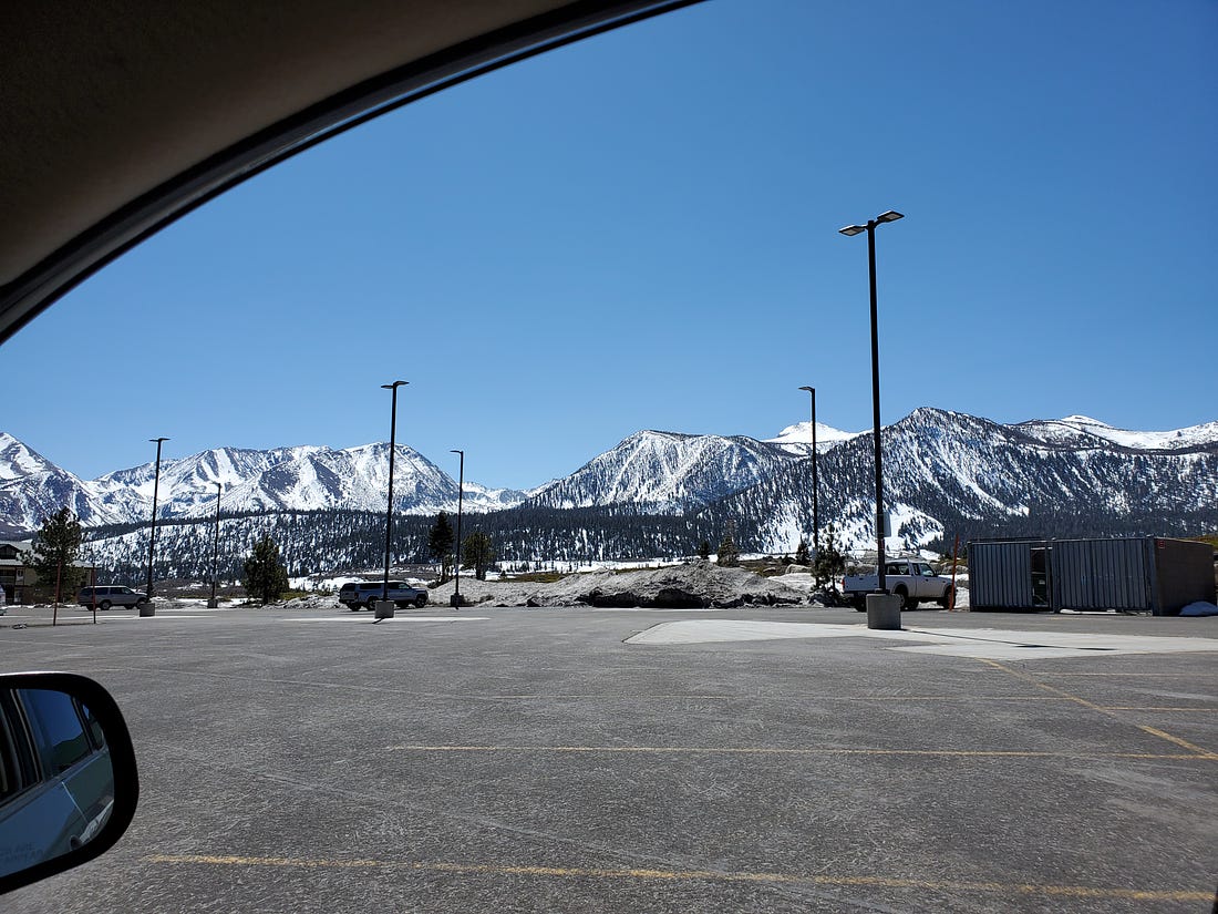 Image of snow bedecked Sherwin Mountains in background, an empty park lot in the foreground.