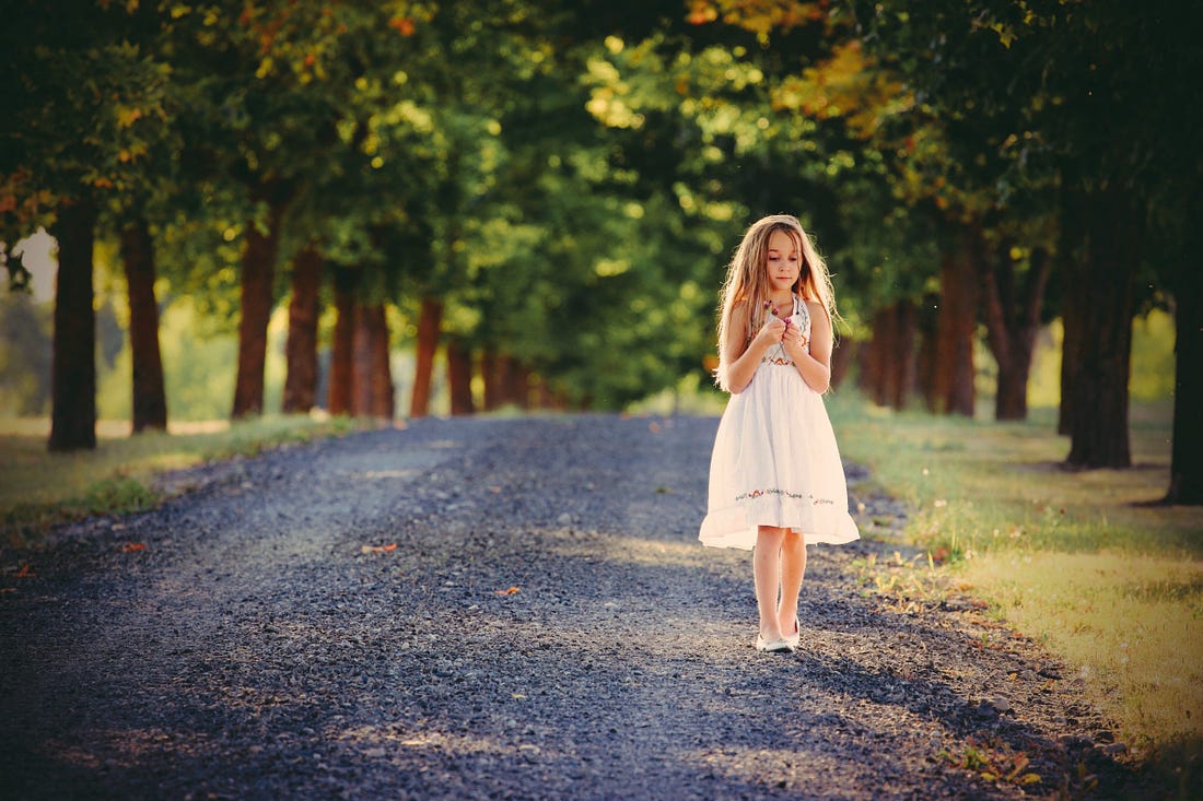 Young girl walking down a country road wearing a dress.