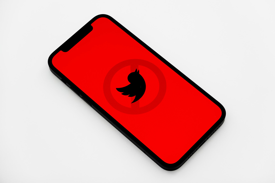 Illustration of Twitter logo against a red background with a circle and a slash through it. (Jeremy Zero / Unsplash)