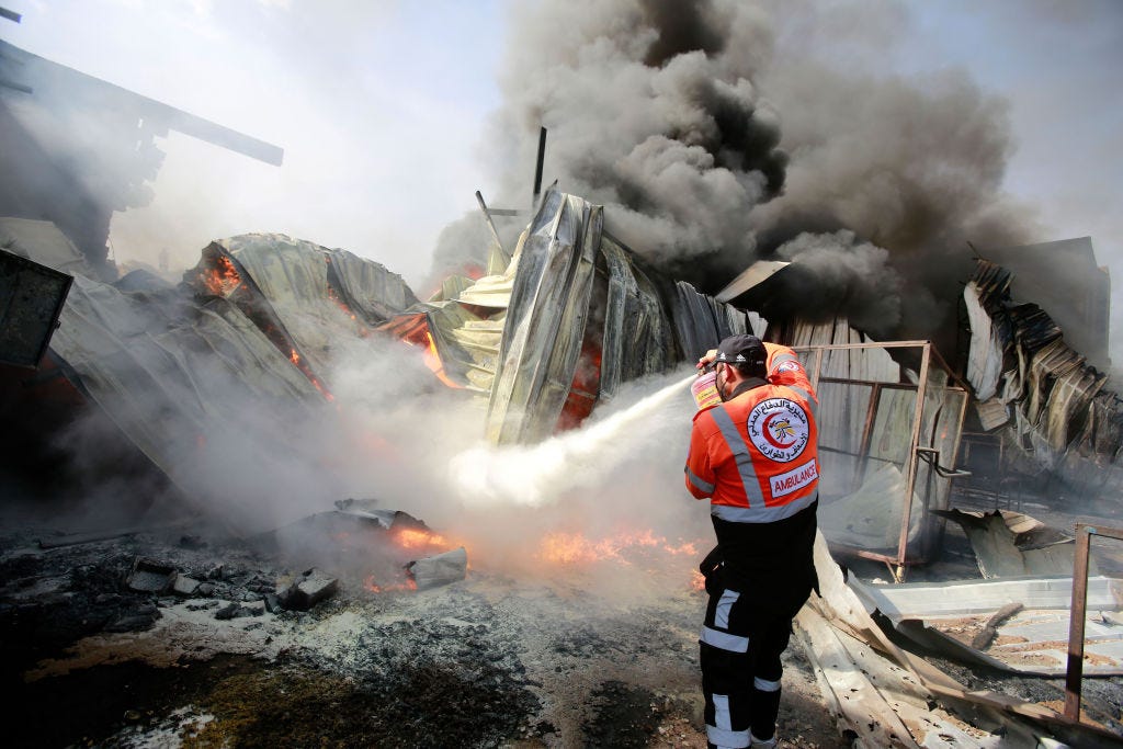 A Palestinian firefighter puts out a fire at a sponge factory after it was hit by Israeli artillery shells. (Ahmed Zakot / Getty Images)