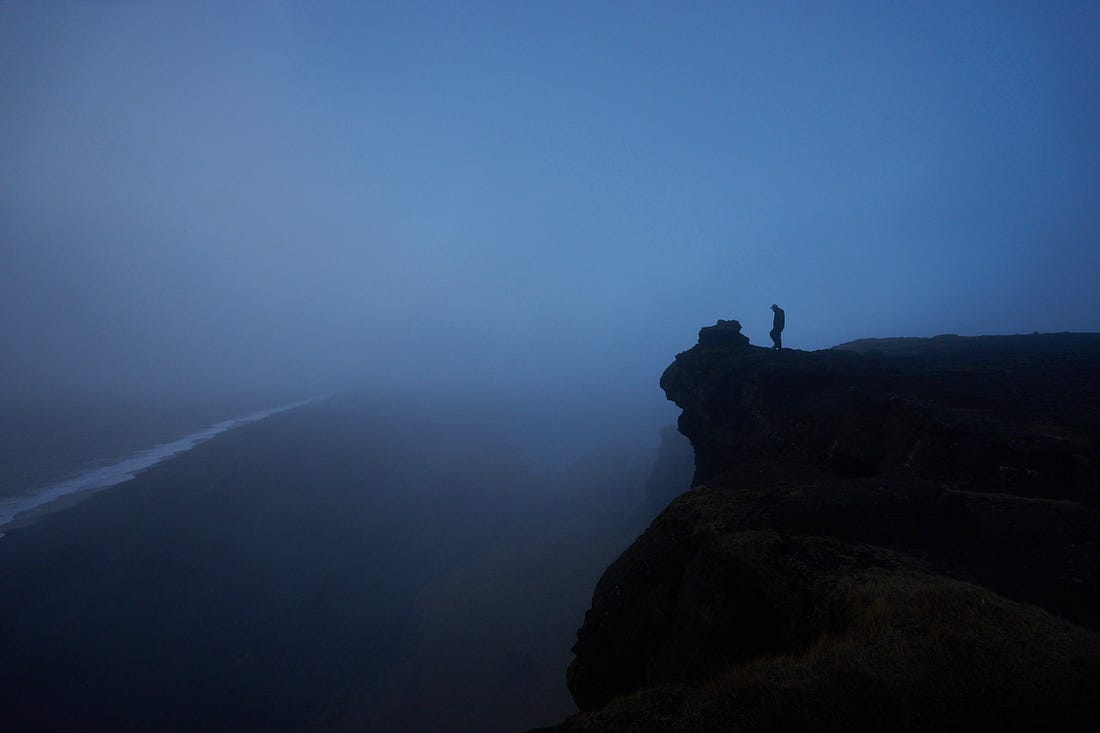 man on the edge of a cliff at night for article by Larry G. Maguire