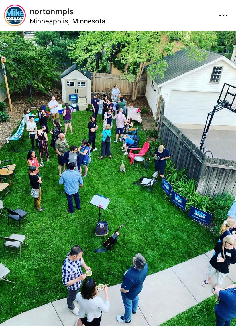 neighbors gathered in a back yard, surrounded by Mike Norton for Minneapolis Council yard signs