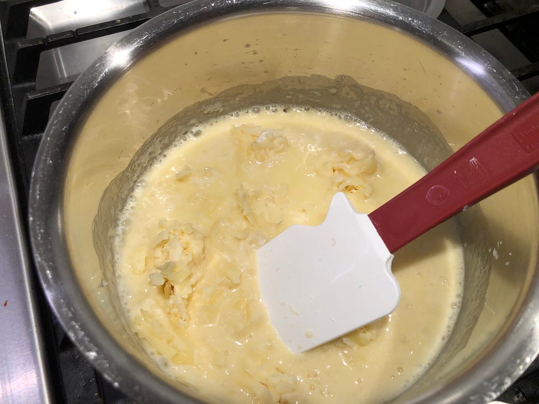 Cheese and cornstarch being stirred into the white wine and melting