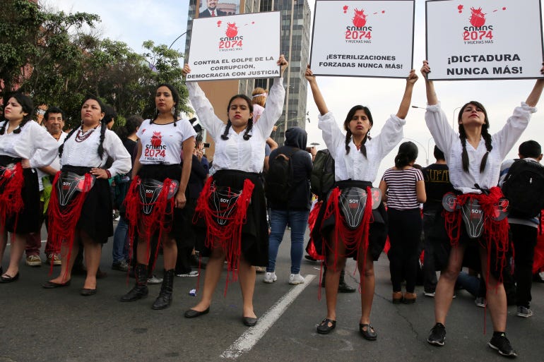 Women hold signs reading 'We are 2,074 and more, forced sterilisations never again' during a protest against violence against women in Lima, Peru, in 2017 [File: Mariana Bazo/Reuters]