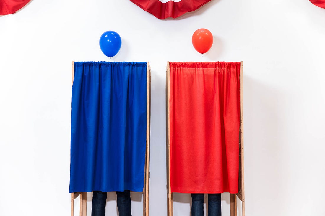 An occupied blue voting booth with a blue balloon next to an occupied red voting booth with a red balloon
