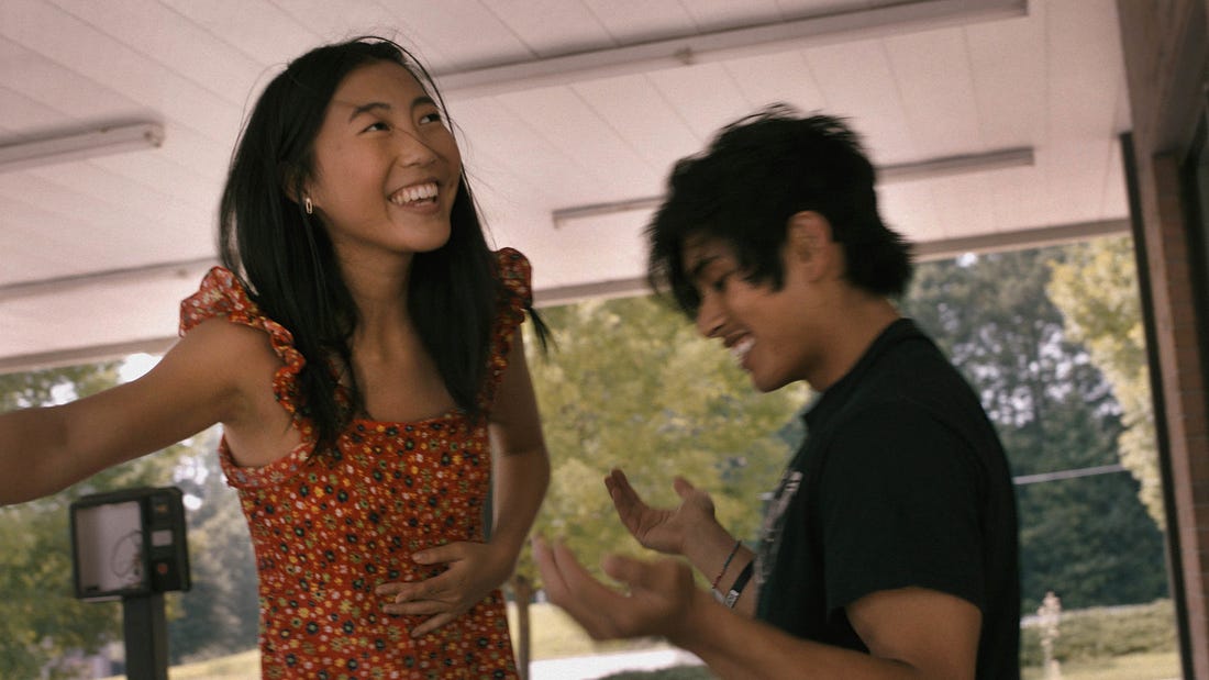 A still from the film 'Beast Beast': Two teens, an asian girl and a latino boy, are smiling together, hanging out in an abandoned Sonics fast food joint, almost dancing.