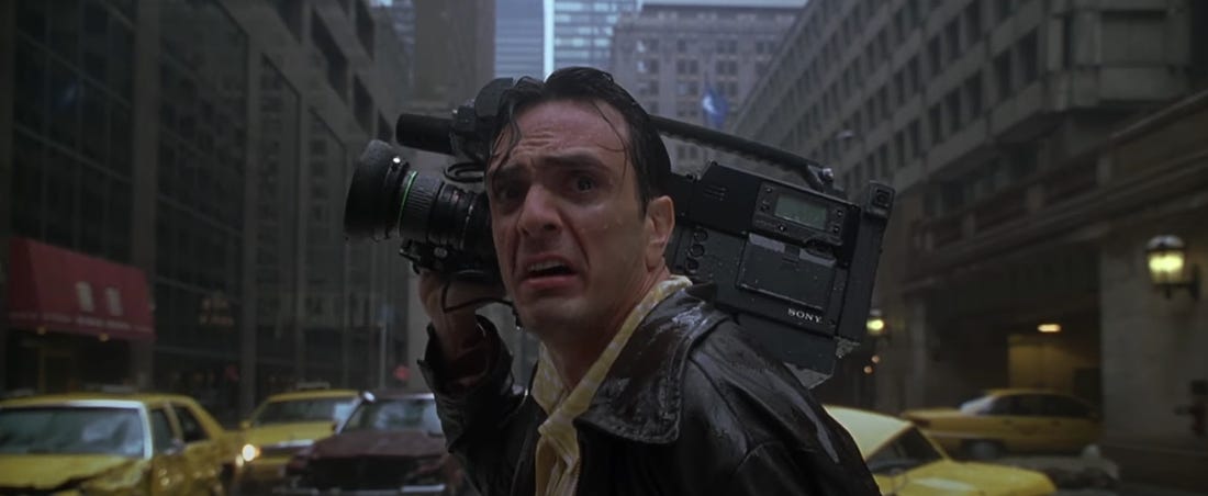 Hank Azaria's news cameraman character, looking back in shock at the giant legend Godzilla, in New York street rain. From the 1998 film 'Godzilla'