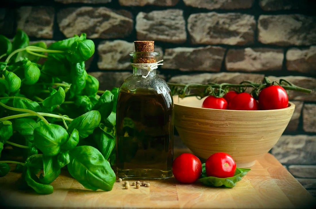 basil and tomatoes and olive oil sitting on a cutting board