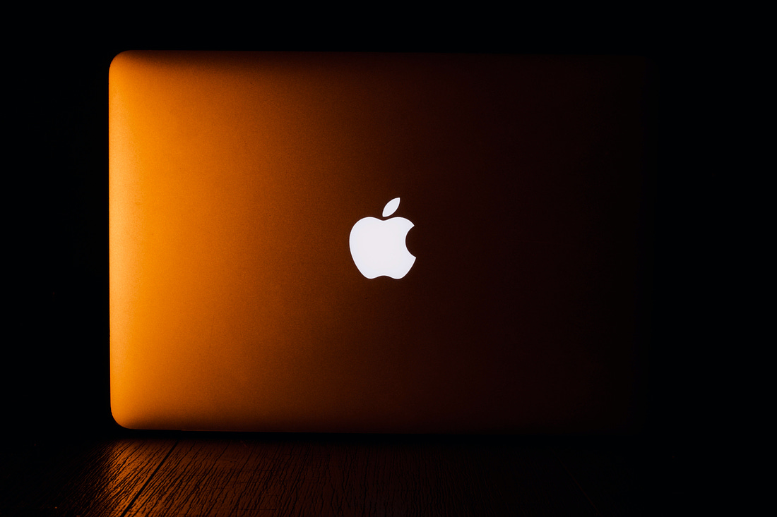 Photo of a MacBook cast in orange light. (Aditya Joshi / Unsplash)