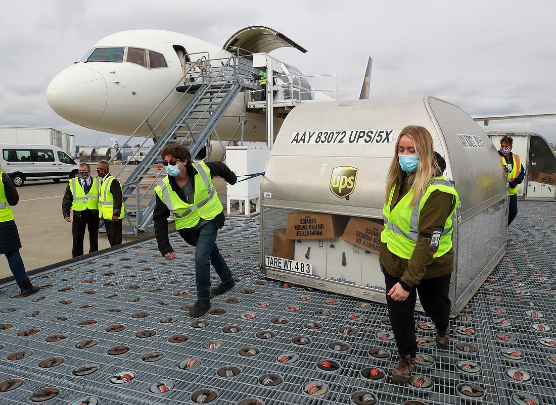 UPS employees move one of two shipping containers containing the first shipments of the Pfizer and BioNTech COVID-19 vaccine a ramp at UPS Worldport in Louisville, Kentucky, on December 13, 2020. The flight originated in Lansing, Michigan. (Photo by Michael Clevenger - Pool/Getty Images)