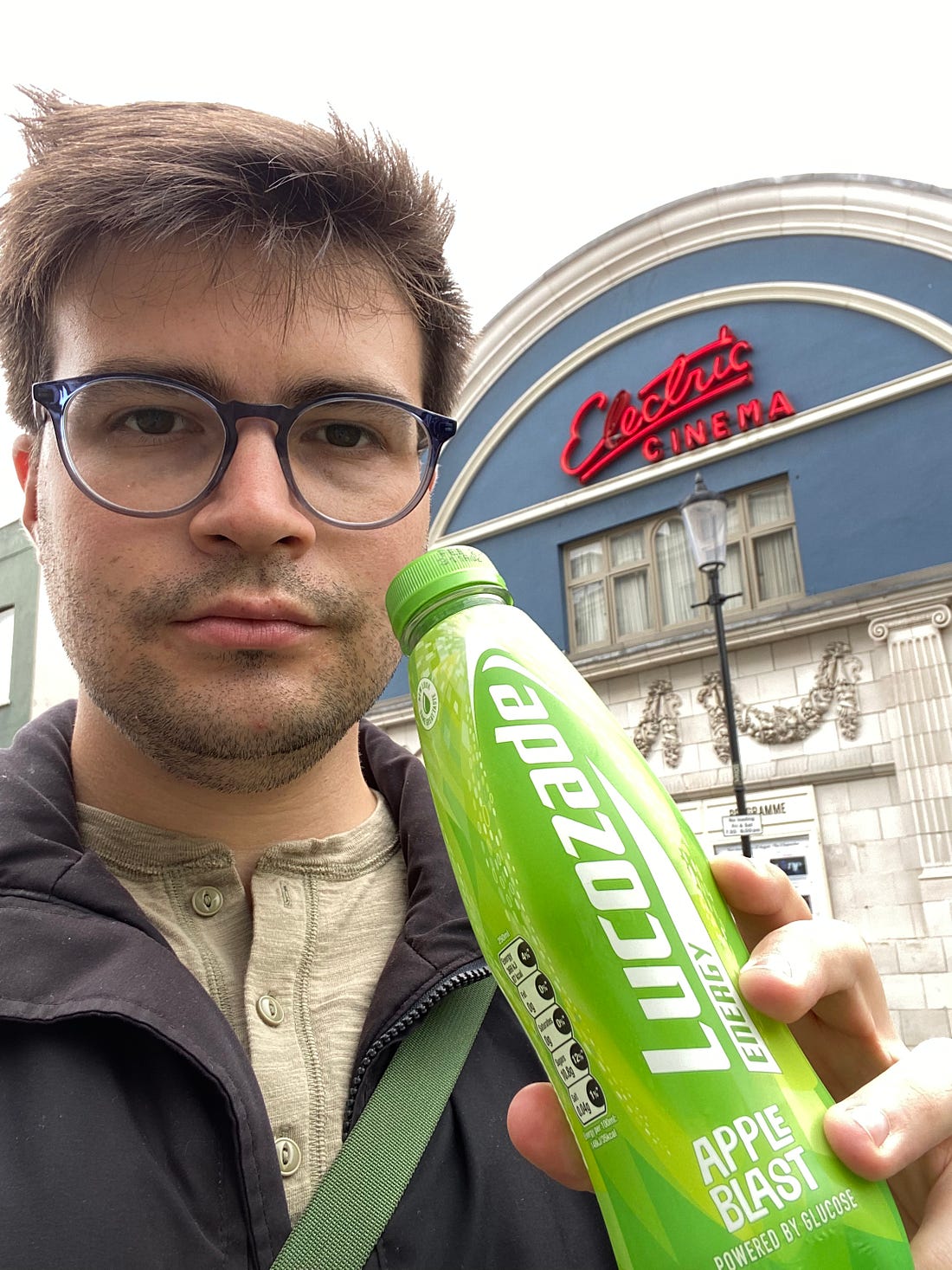 The author standing with a Lucozade Apple Blast in front of Electric Cinema, a movie theater in Notting Hill.