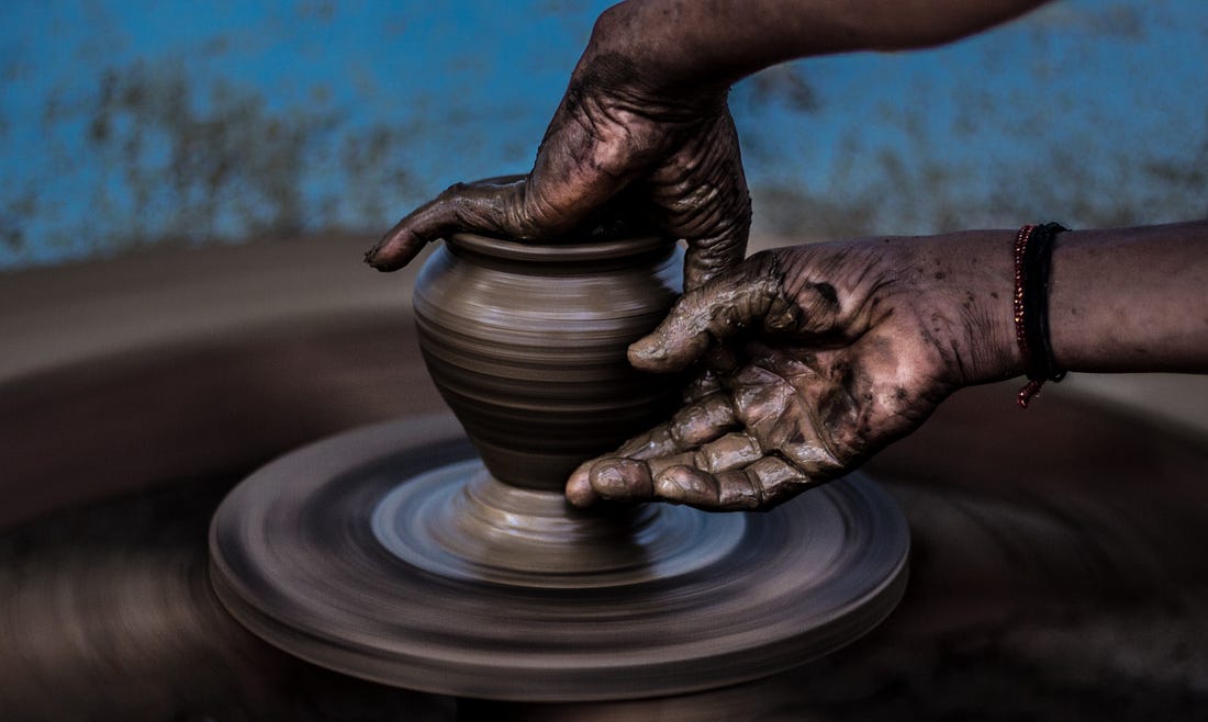 image of hands forming a clay pot for article titled “what is an artist” by Larry G. Maguire
