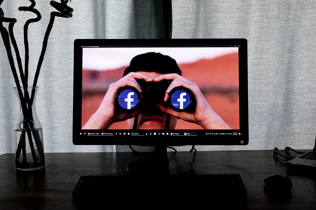 Photo of a computer on a desk showing a photo of a man viewing binoculars with Facebook logos on the outer lenses. Glen Carrie / Unsplash