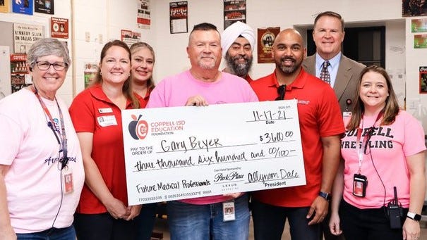 Coppell ISD Education Foundation volunteers present a giant check to Coppell High School teacher Gary Beyer