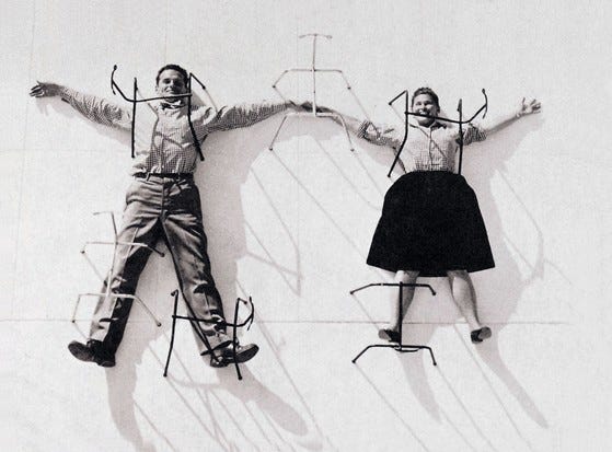 An archive photo of Charles and Ray Eames pinned to a white board with Eames Hang it Alls