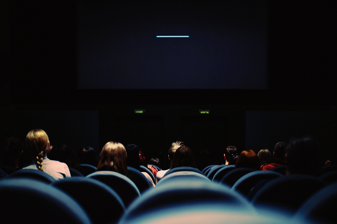 Behind a crowd of people. seated in a dark movie theater. Behind a crowd of people. seated in a dark movie theater.