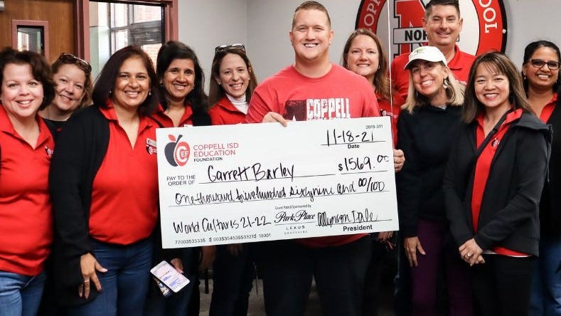 Coppell ISD Education Foundation volunteers present a giant check to Coppell Middle School North teacher Garrett Barley