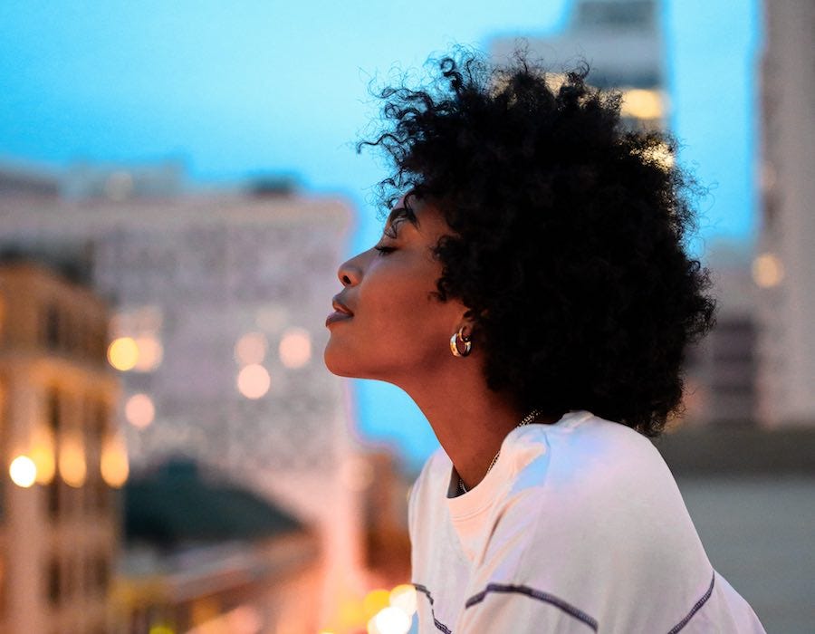 Confident young woman gazing at city lights from above