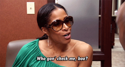 A gif of Sheree Witfield sitting on a chair and saying, "Who gon' check me, boo?"
