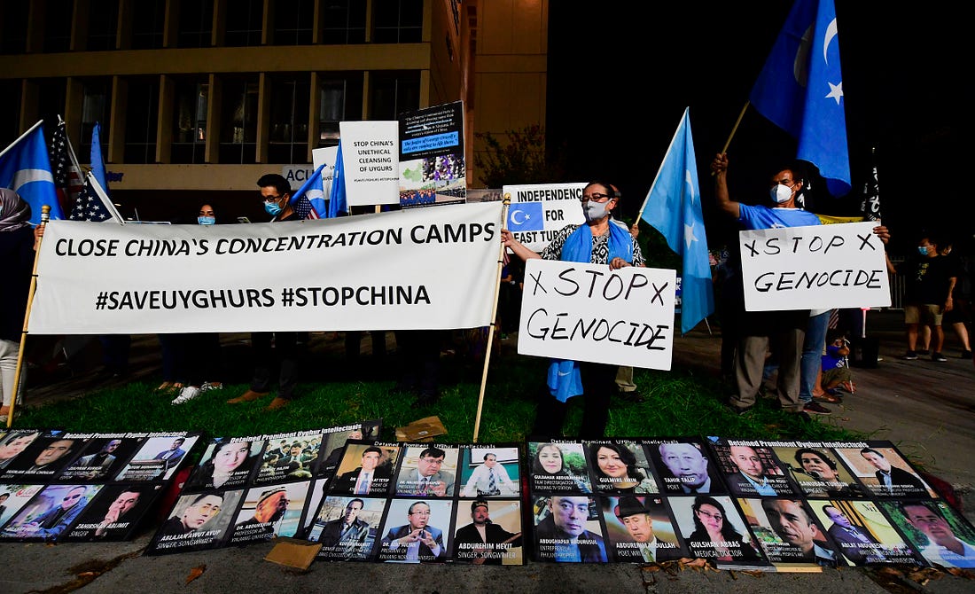 Protesters stand behind a display of photographs of prominent Uighur intellectuals detained by China as they gather across from the Chinese Consulate in Los Angeles on October 1, 2020 during a global day of action called by "Resist China" (#ResistChina), a global campaign against the regime of the Chinese Communist Party. (Photo by Frederic J. BROWN / AFP) (Photo by FREDERIC J. BROWN/AFP via Getty Images)