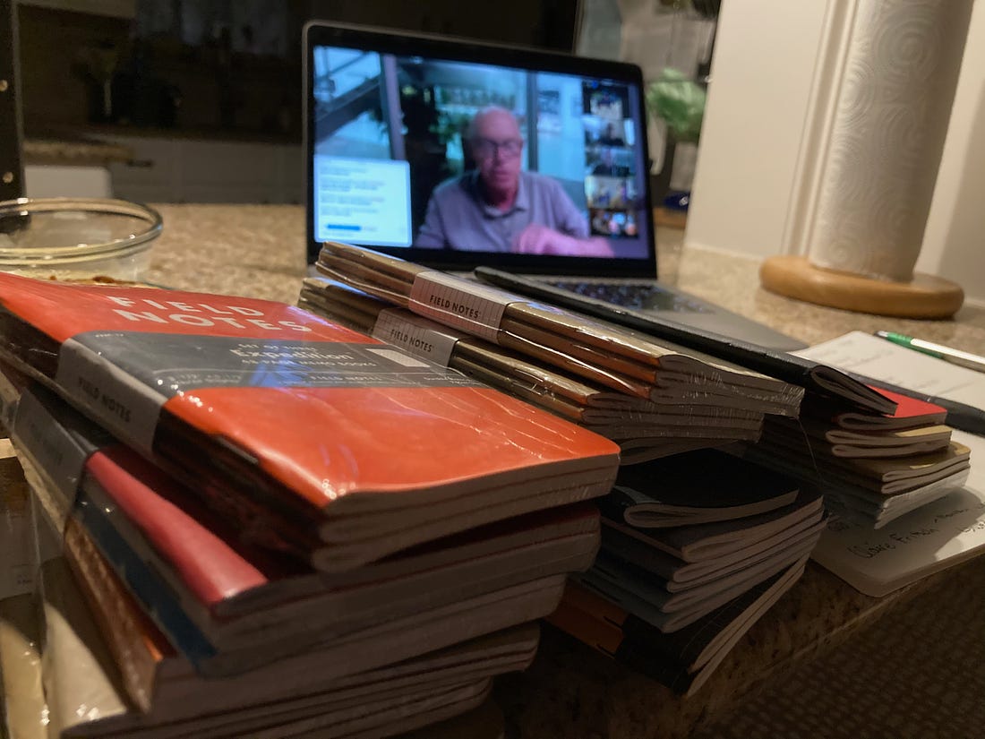Computer showing video chat with Jim Coudal of Field Notes Brand, with a few dozen notebooks scattered on the table in front of the computer.