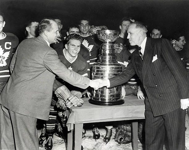 Manger and head coach Hap Day of the Toronto Maple Leafs shakes hands with NHL President Clarence Campbell after the Maple Leafs defeated the Detroit...