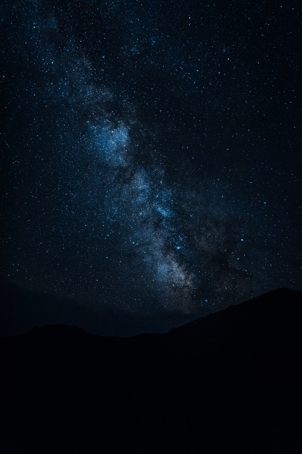 silhouette of mountain under starry night sky