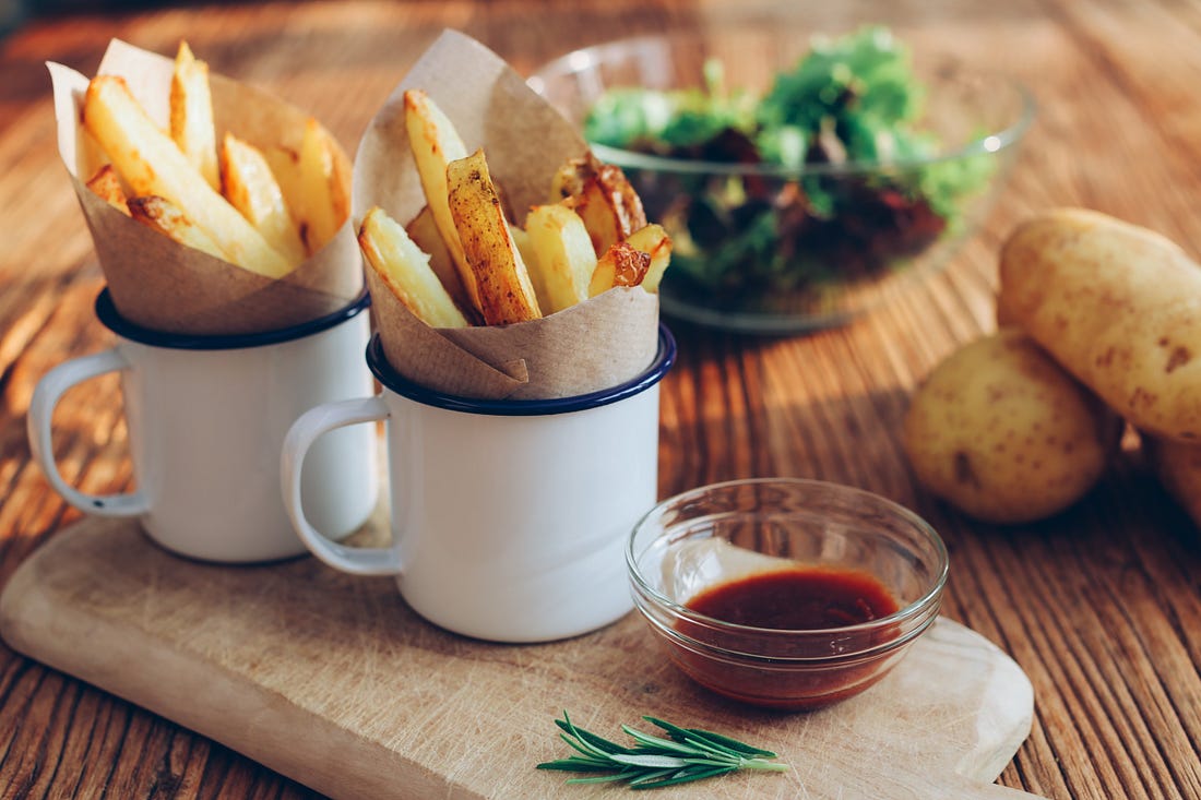 Two cups filled with French fries.