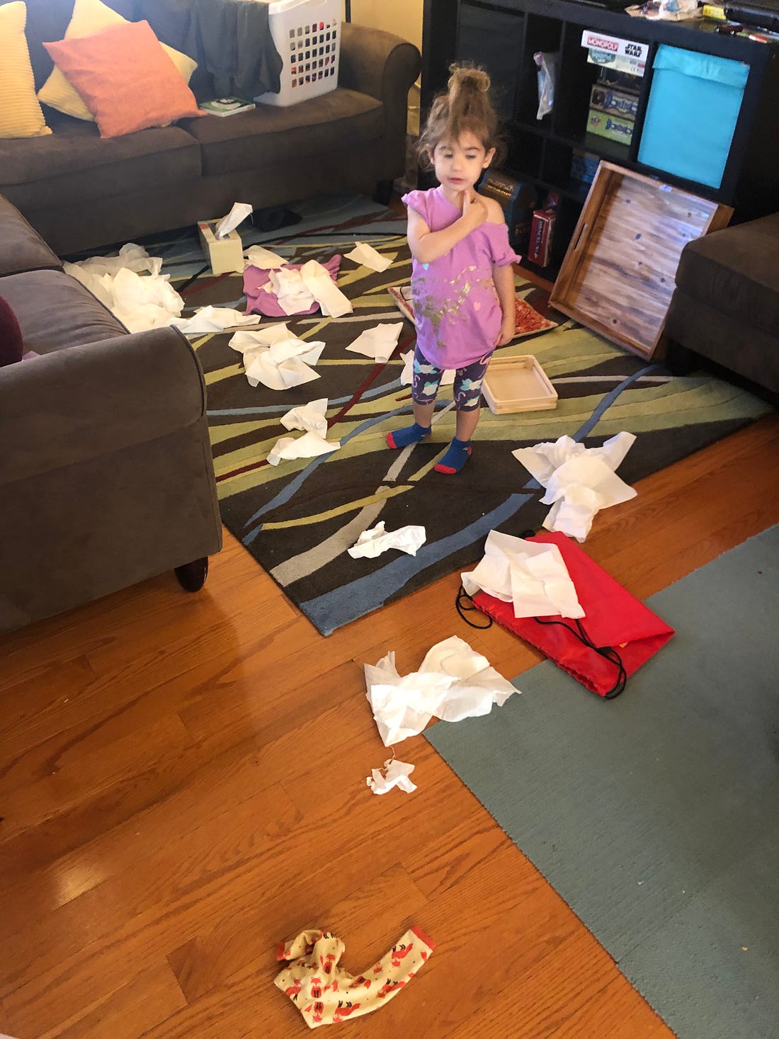 Photo shows a 3 year old who has pulled all of the tissues out of the box and scattered them everywhere.