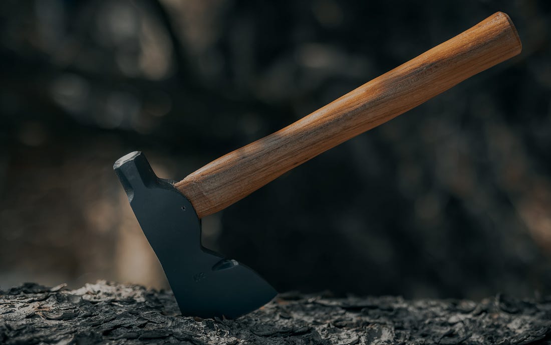 A hatchet buried in wood. (Clay Banks / Unsplash)