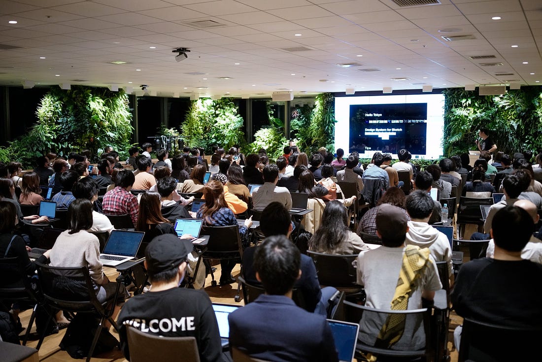 A photo from a meetup in Tokyo with almost 100 people watching a presentation.