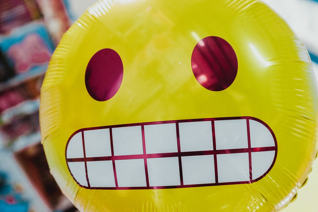 Photo of a ballon in the shape of a grimacing emoji. (Bernard Hermant / Unplash)