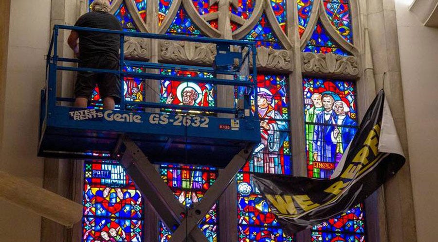 Man on scaffolding removing stained glass window