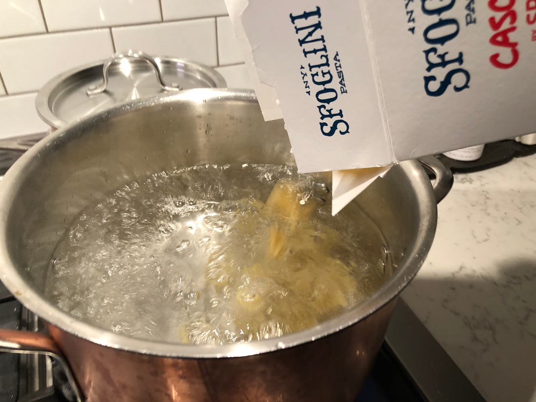 Cascatelli pasta being poured into a pot of boiling water