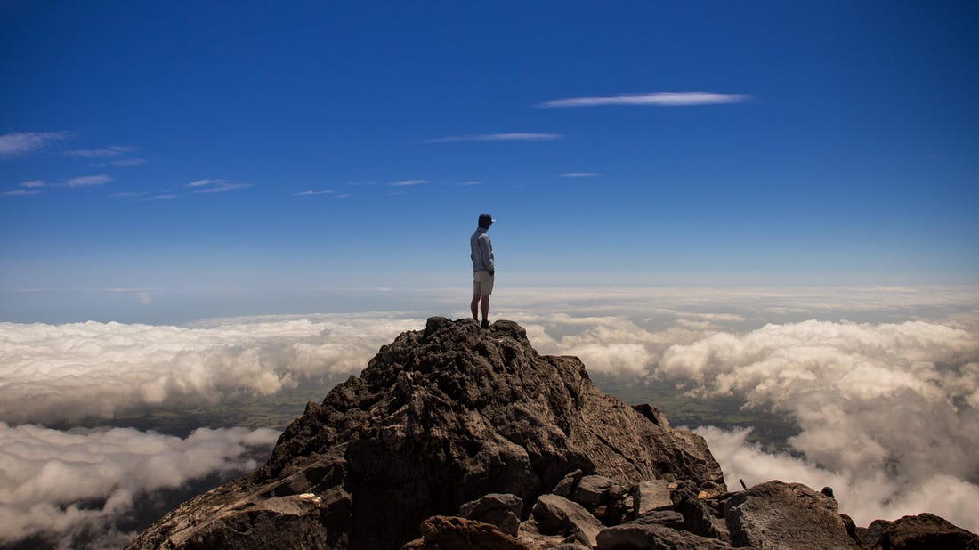 Man standing on top of a mountain for article titled “The Psychological Aspects of Optimal Experience”