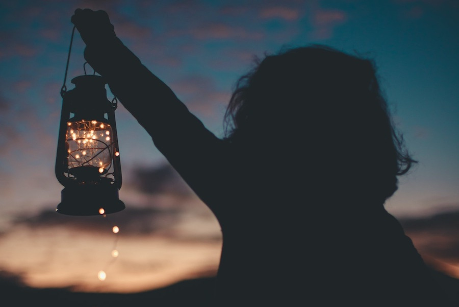 Person holding a lantern at sunset