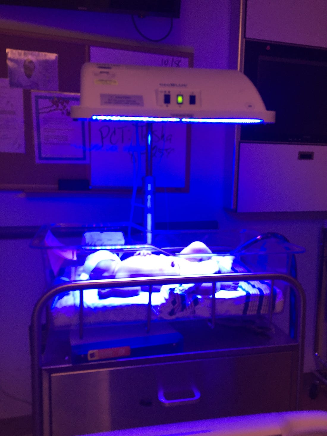 Photo of a newborn in a bassinette under blue light