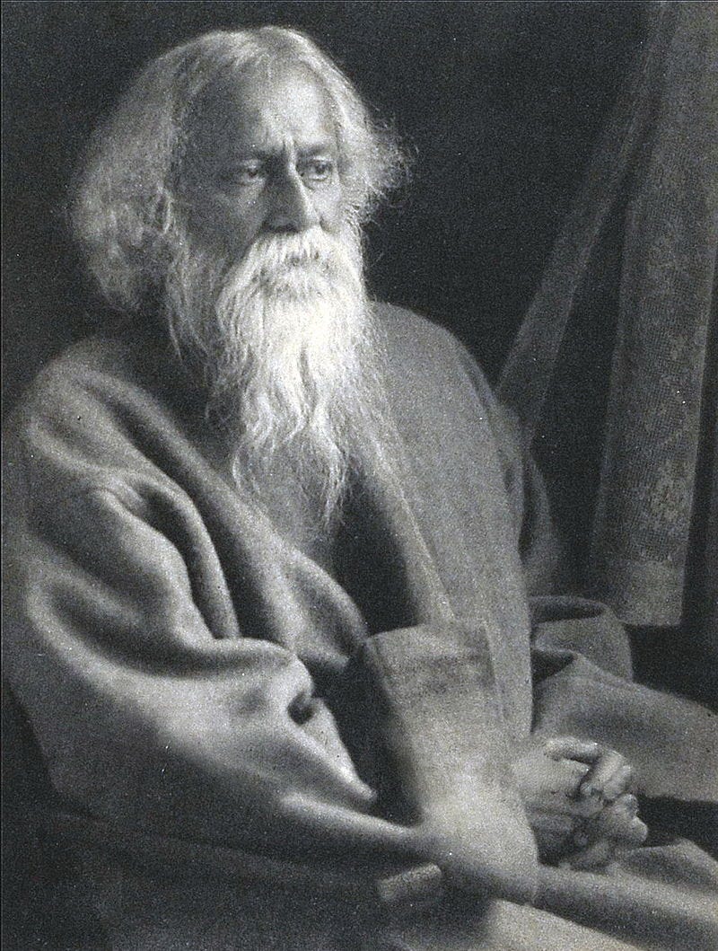 A late-middle-aged bearded man in grey robes sitting on a chair looks to the right with serene composure.