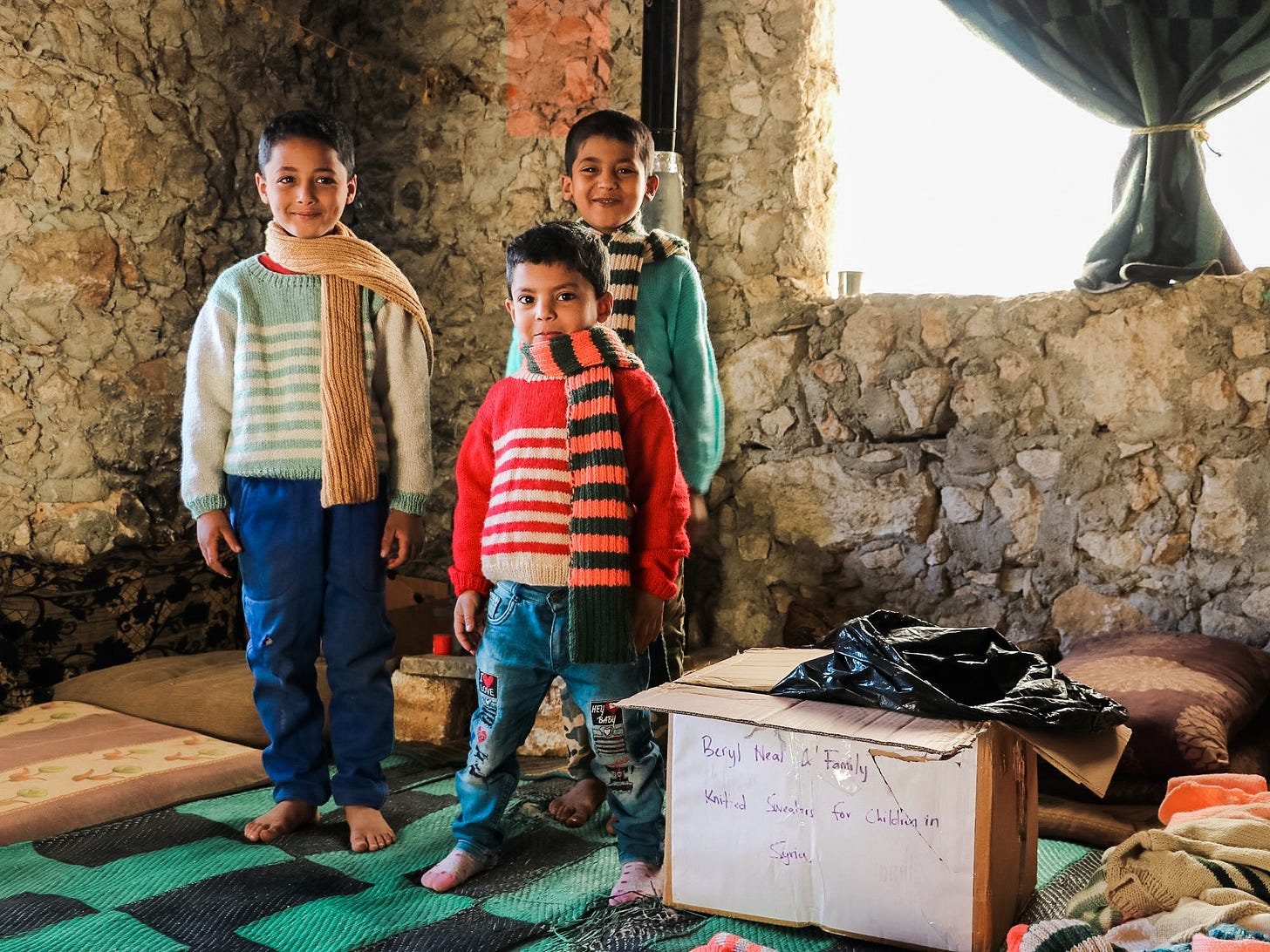 3 kids wearing knitted sweaters and scarves