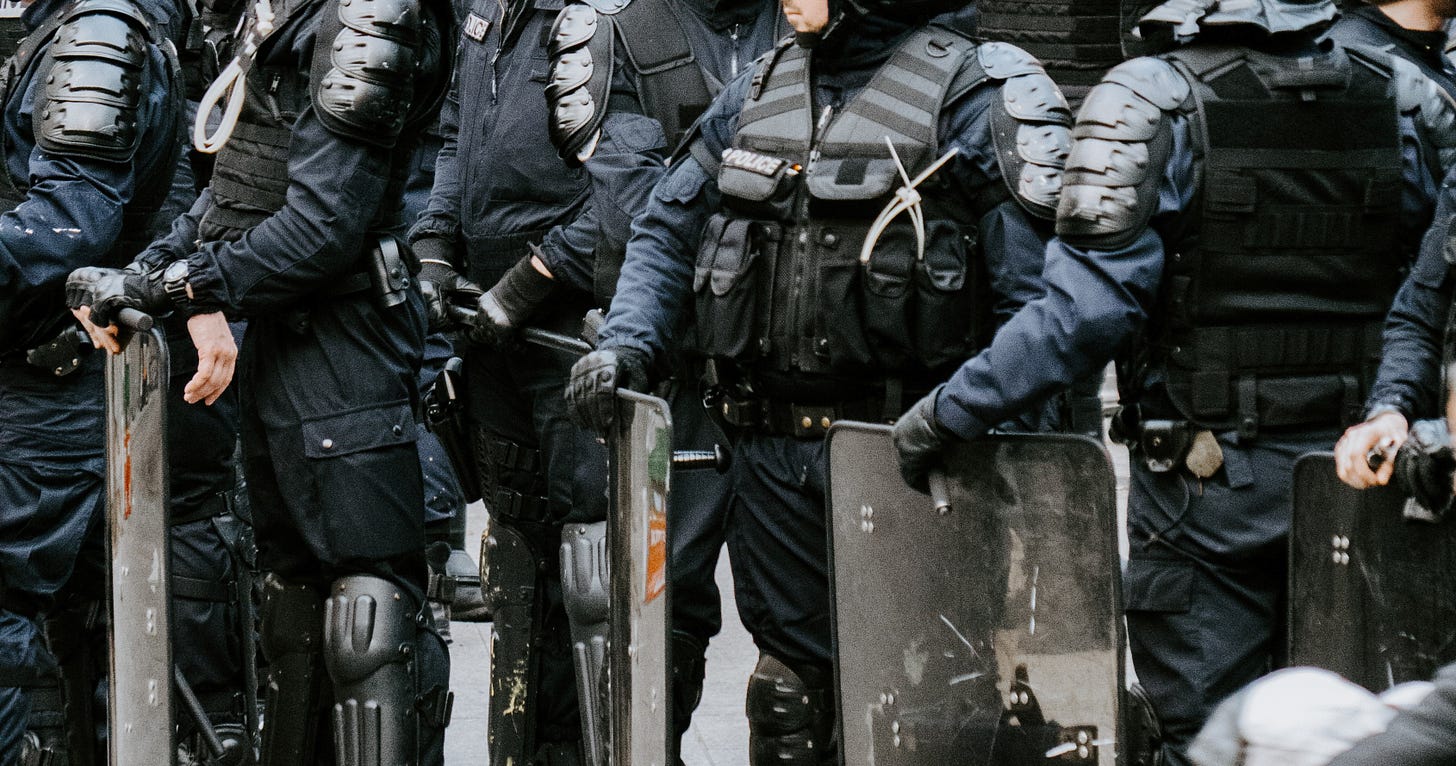 A row of riot police holding shields.