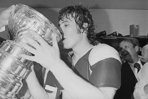 Philadelphia Flyers center Bobby Clarke drinks champagne from the Stanley Cup in their locker room after winning the sixth and final game of the...